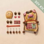 DIY kit materials for Handmade Woodland Pocket Piglet Decor arranged beside the finished design on a neutral background