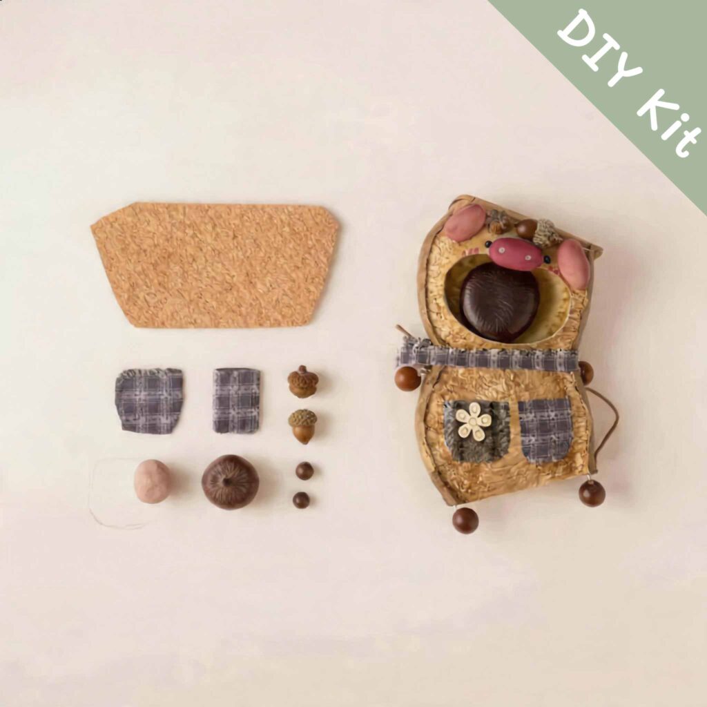 DIY kit materials for Chestnut Pocket Pig Pod Doll arranged beside the finished design on a neutral background