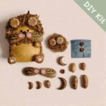 Curly Whisker Hamster pod doll DIY kit with natural seed pod parts, curly hair piece, whisker cheeks, blue fabric apron, and handmade accessories