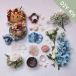 DIY kit flat lay for a seaside flower pod doll with shells, starfish, flowers, and ocean-inspired blue decorative pieces