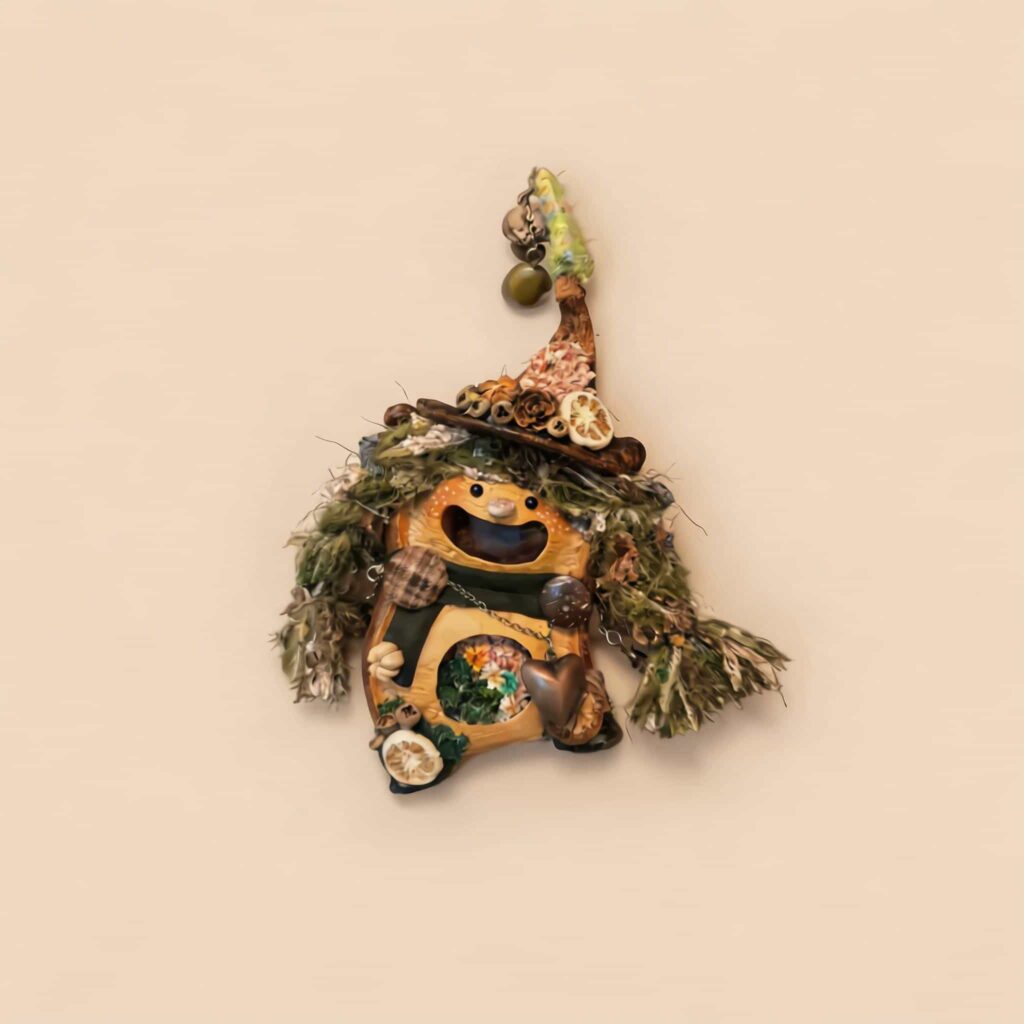 Open-Mouth Pod Doll Moss Heart Witch with mossy green textured hair, tall witch hat, and dangling heart charm on a neutral background