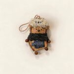 Pod Doll Midnight Scarf Poodle with fluffy curly cream hair, tiny bow, black scarf, and patchwork details on a neutral background
