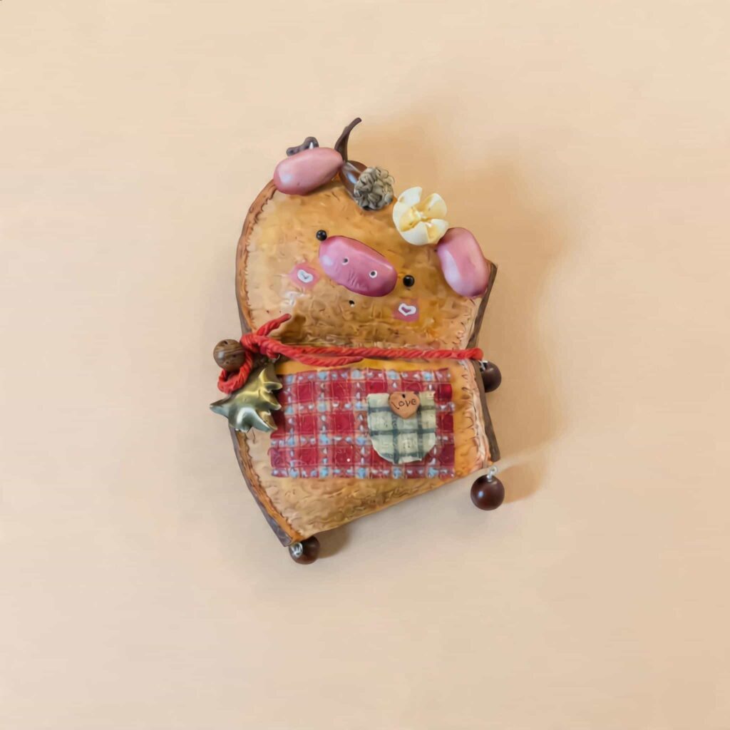 Handmade Cozy Piglet Decor with pink piggy details, red cord accent, and plaid pocket on a neutral background