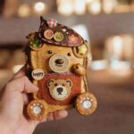 Handheld Happy Pocket Bear pod doll showing textured pocket detail, cute bear face, and handcrafted woodland decorations