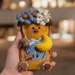Handmade Moonlit Blue Blossom Bear pod doll held in hand with dreamy warm background