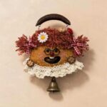 Front view of a handmade hanging pod doll with red curly pigtails, daisy accent, and dangling bell