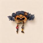 Front view of a handmade open-mouth pod doll with blue yarn pigtails and dangling bead legs