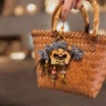 Open-mouth pod doll charm hanging from a woven basket as a handmade bag accessory