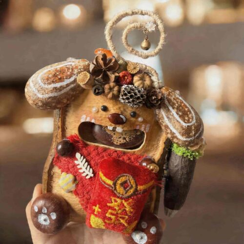 Front view of an open-mouth pod doll featuring a bright red fortune pouch, botanical crown, and cheerful handcrafted face