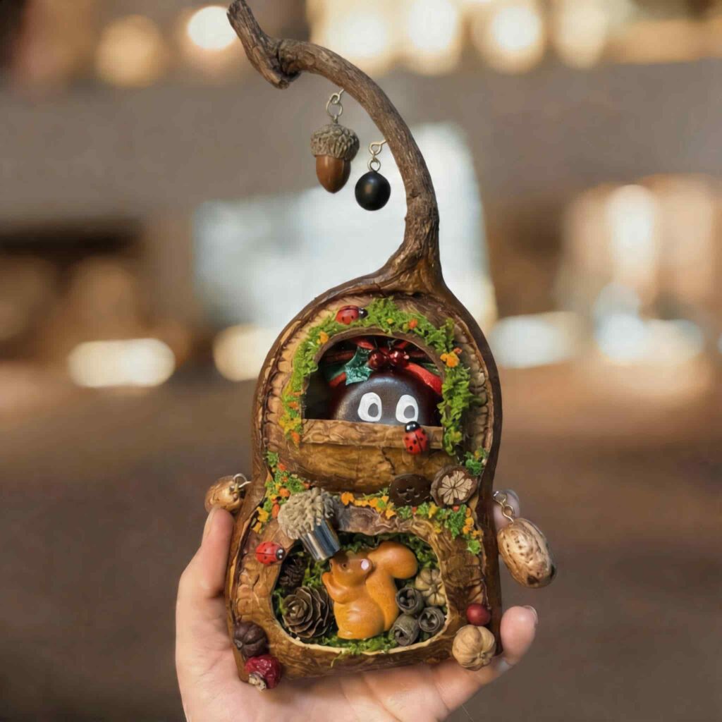 Front view of a hanging pod house ornament featuring a tiny squirrel inside a mossy woodland hollow