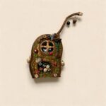 Front view of an open-mouth pod doll featuring a bright red fortune pouch, botanical crown, and cheerful handcrafted face