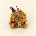 Handmade Fuzzy Glasses Monster Pod Doll held in hand, showing fluffy texture, round glasses, pointed hat, and colorful outfit details
