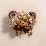 Handmade Pod Doll Mocha Ribbon Bear held in hand, showing soft curly texture, teddy bear styling, and neutral brown tones