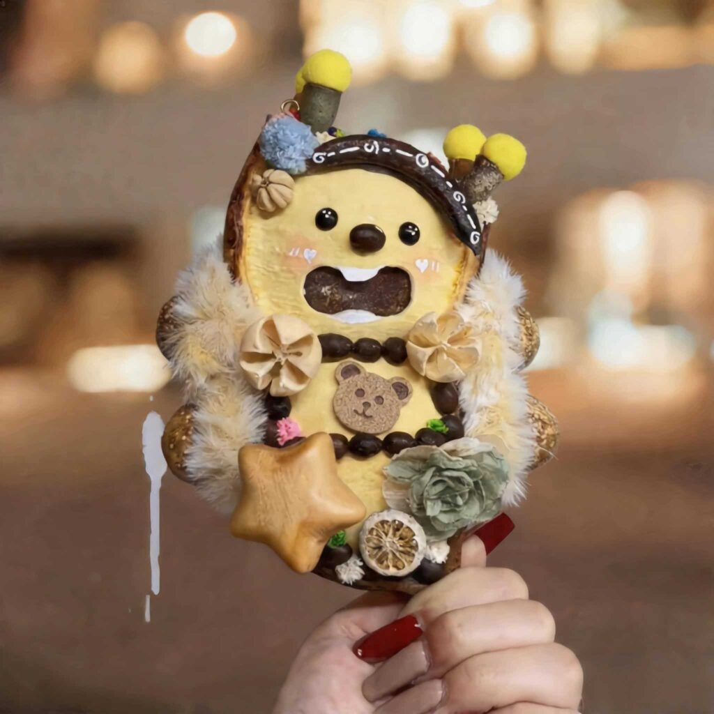 Handmade open-mouth pod doll with butter-yellow bear design held in hand