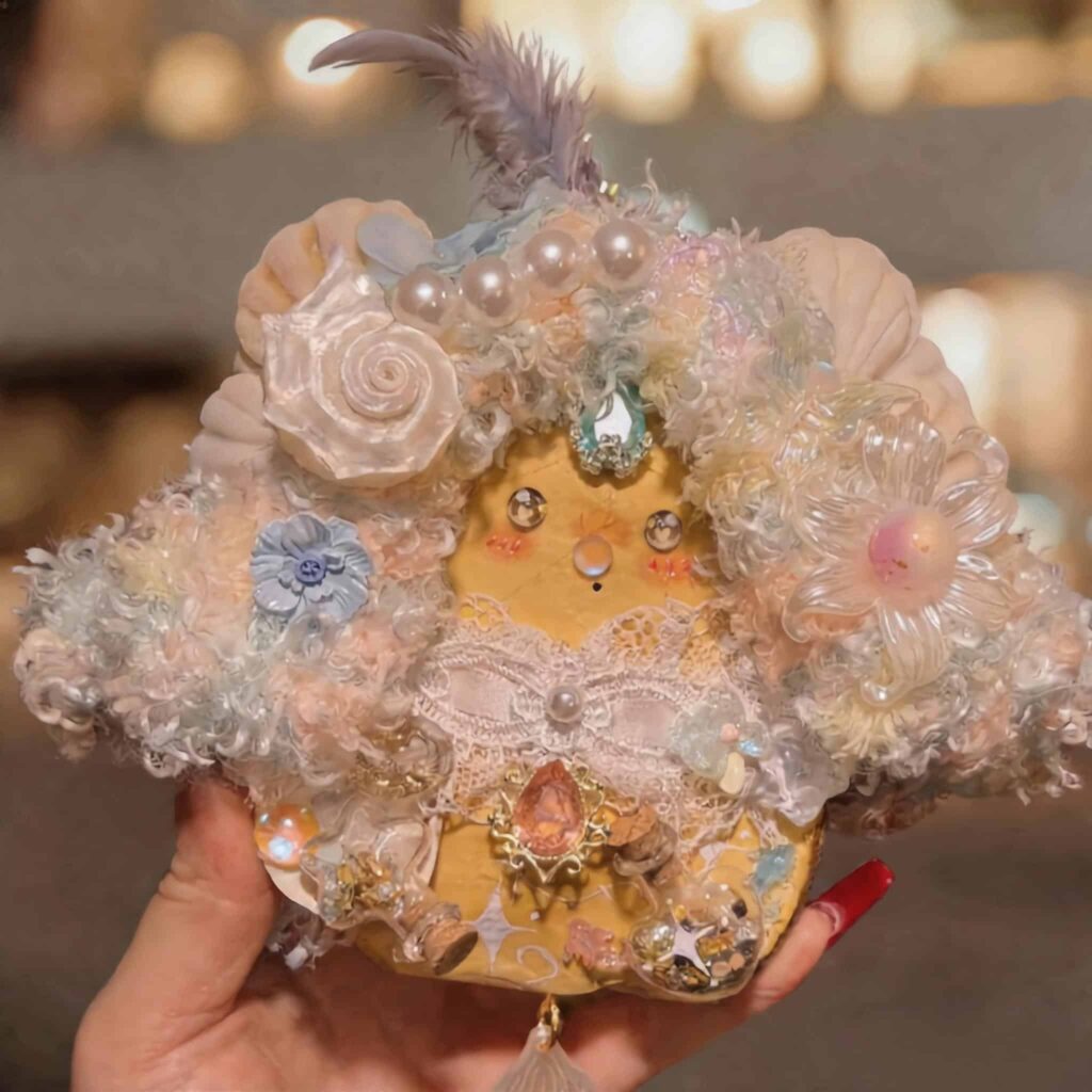Handmade floral pod doll with pastel curls, pearls, lace bow, and tassel detail held in hand