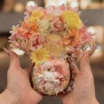Handmade floral pod doll with layered blossoms and kawaii miniature details held in both hands