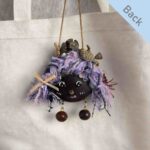 Double-Sided Pod Doll Berry Button Pixie back view hanging on a canvas bag
