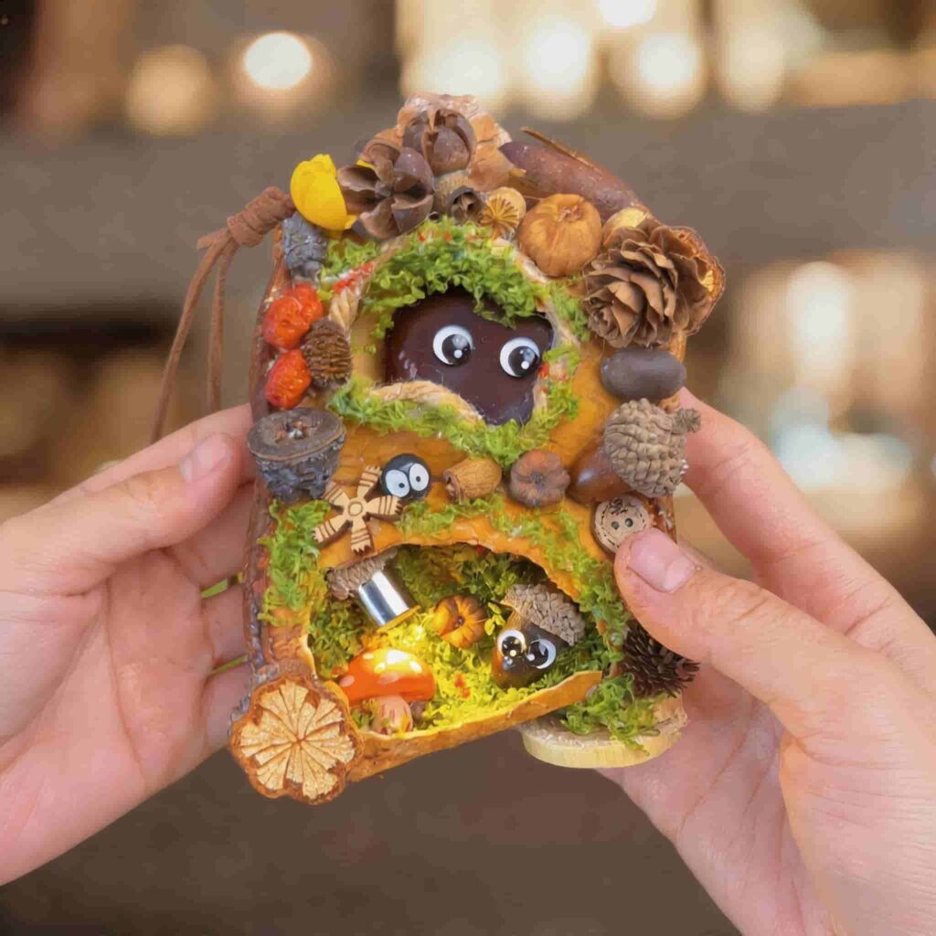 Handmade double-sided pod doll with mossy woodland burrow opening and miniature forest details held in two hands