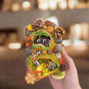 Front view of handmade pod doll with moss opening, woodland decorations, and cozy burrow-style design