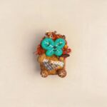 Studio shot of the double-sided pod doll with a magnetic green clover-style face attached on a clean beige background.
