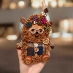 Main finished Pod Doll image showing brown curly fur, decorative glasses, and floral accents