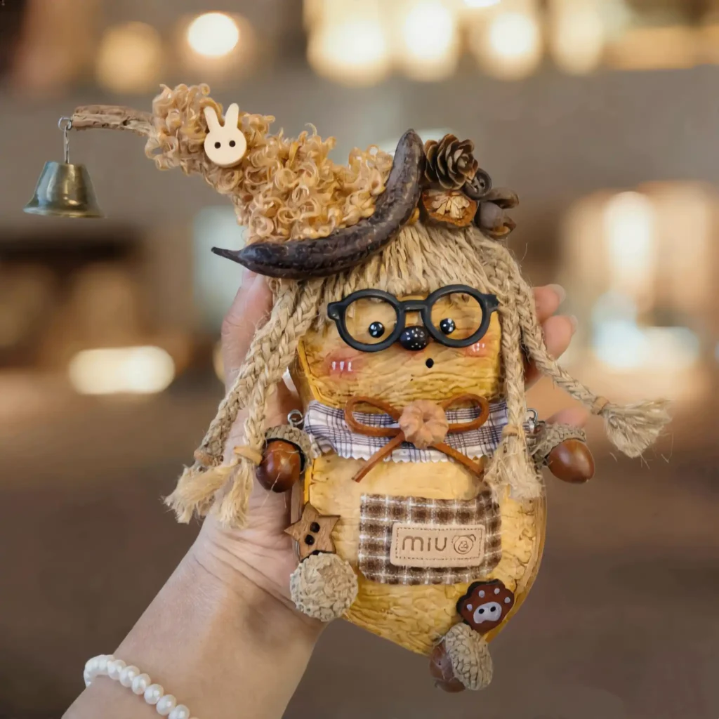 Finished Pod Doll – Bird with Glasses showing seed-pod body, beak, curly hair, bunny charm, and bell