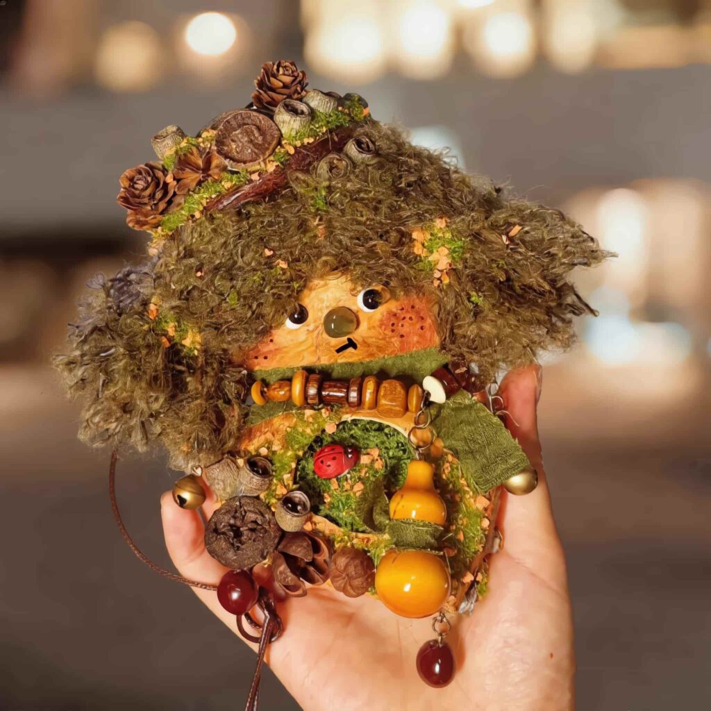 Finished Pod Doll with pinecone crown, mossy hair, orange face and googly eyes