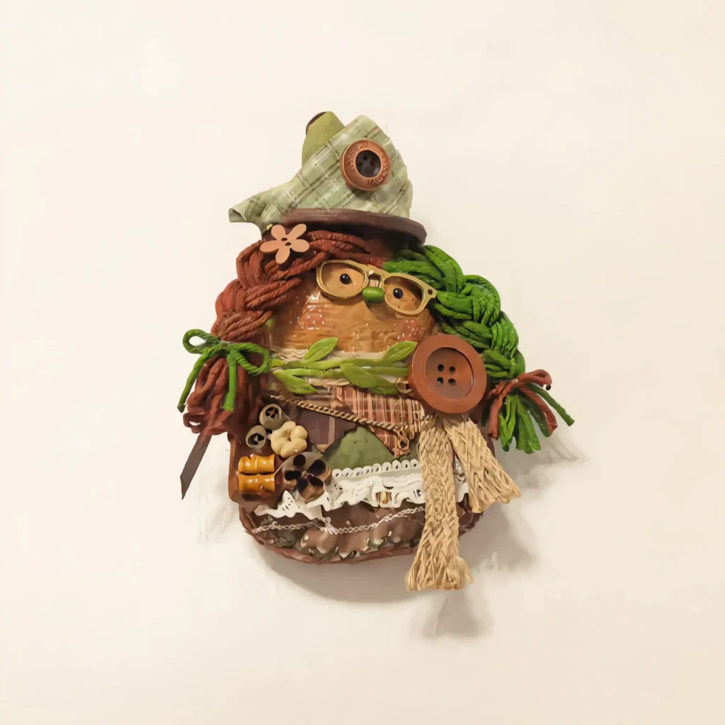 Close-up detail of finished Pod Doll head with orange eye circle and green hat