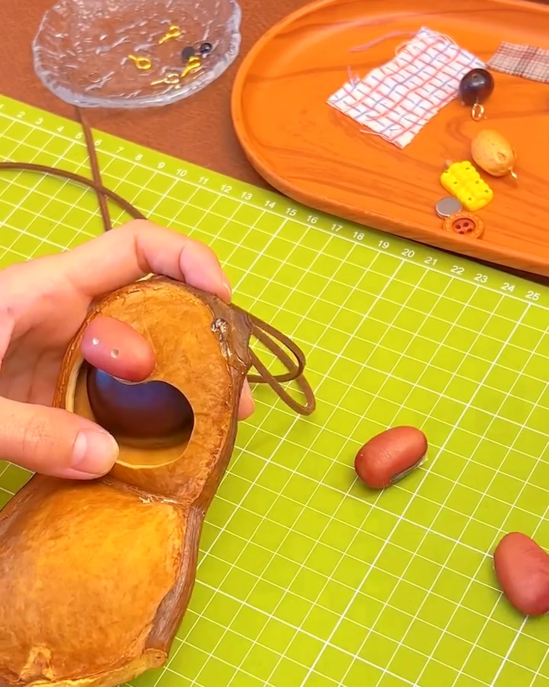 Handmade face details being added to a pod doll made from a natural seed pod shell.
