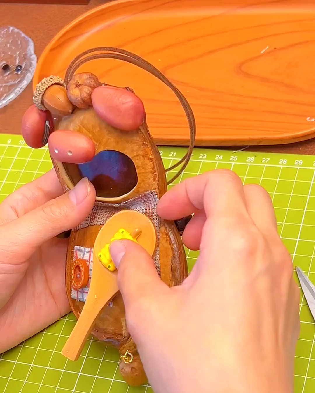 Tiny handmade accessories being added to a storybook-style pod doll character.