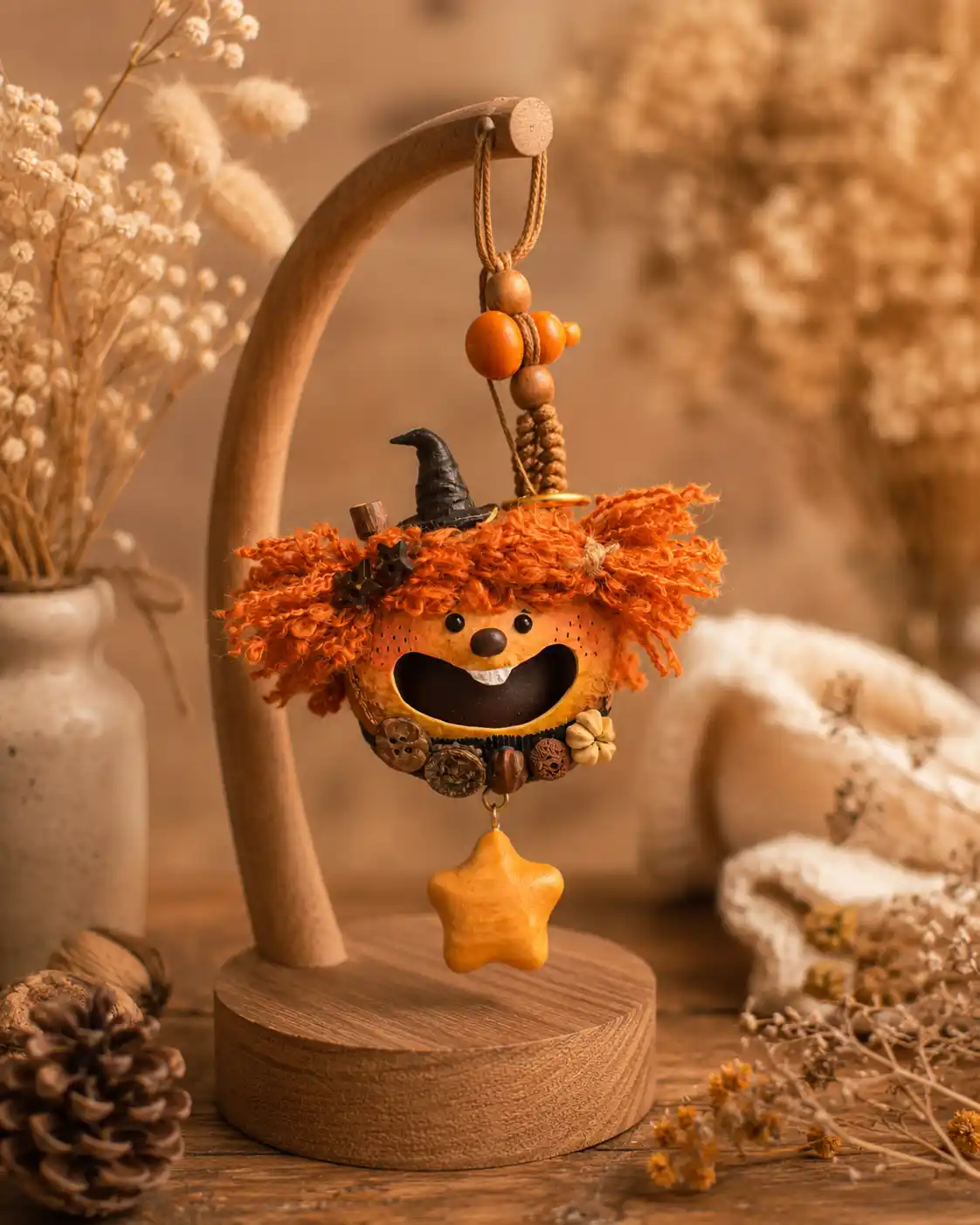 Orange-haired handmade pod doll hanging on a wooden display stand with dried flowers and cozy natural decor