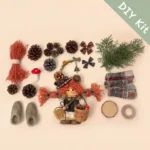 Woodland Witch Pod Doll DIY kit flat lay with orange yarn hair pinecones mushroom basket broom boots and handmade craft materials