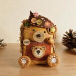 Front view of a handmade bear-inspired Poddoll with a decorated hat, happy badge, knitted outfit, and woven bear detail