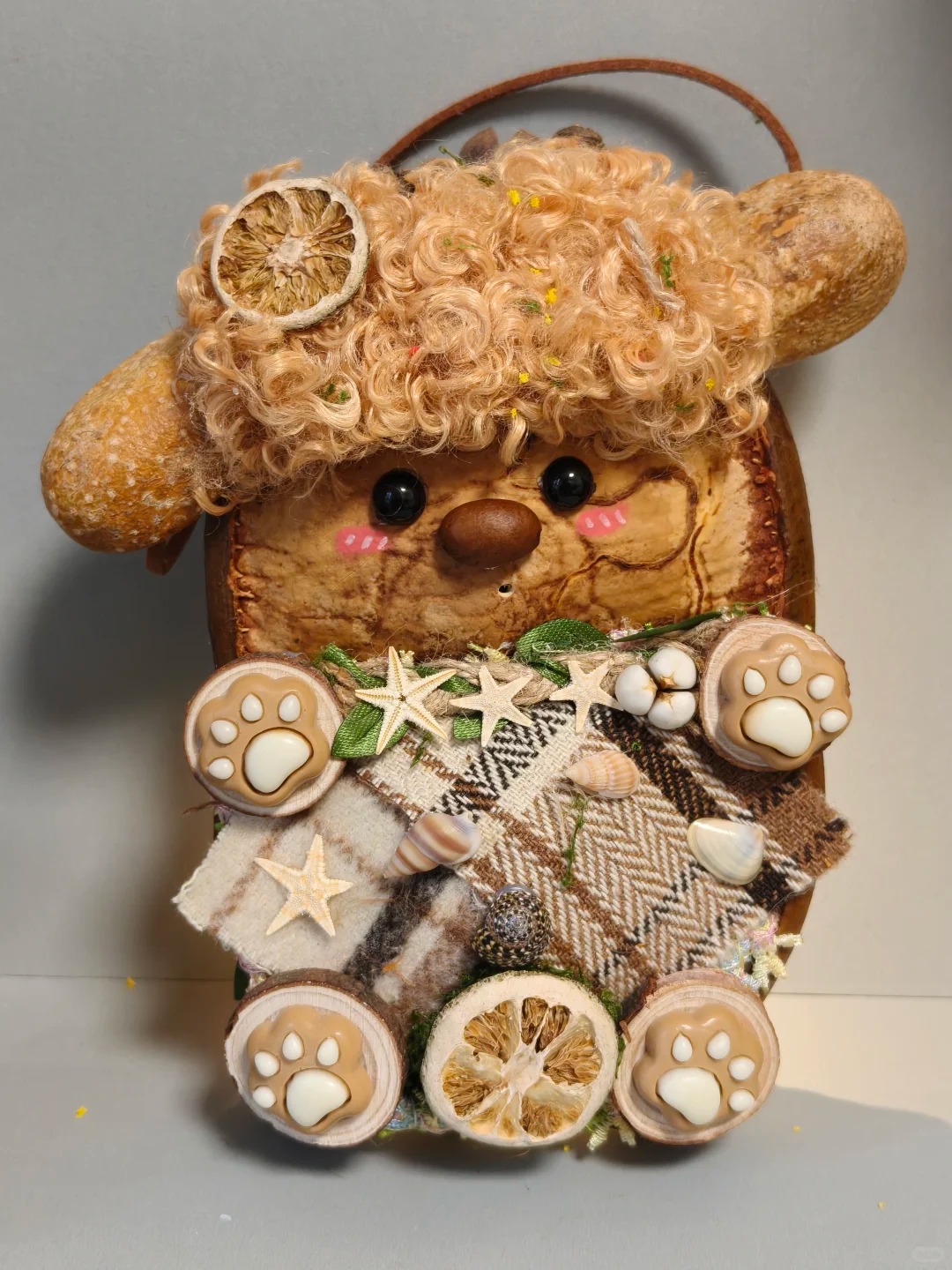 Back view of the same animal-inspired Poddoll with curly hair, layered textiles, shells, star shapes, dried citrus, and paw details
