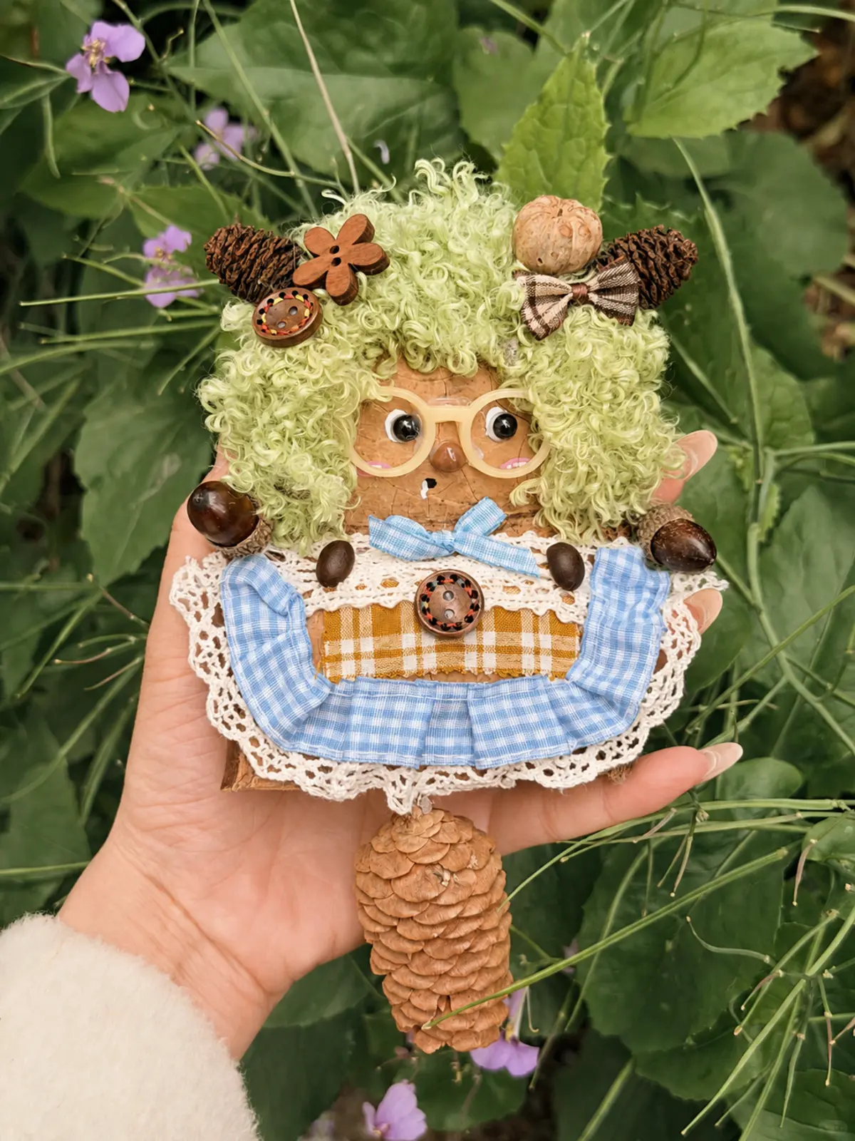 Green-haired handmade Poddoll character with glasses and pinecone details in a garden