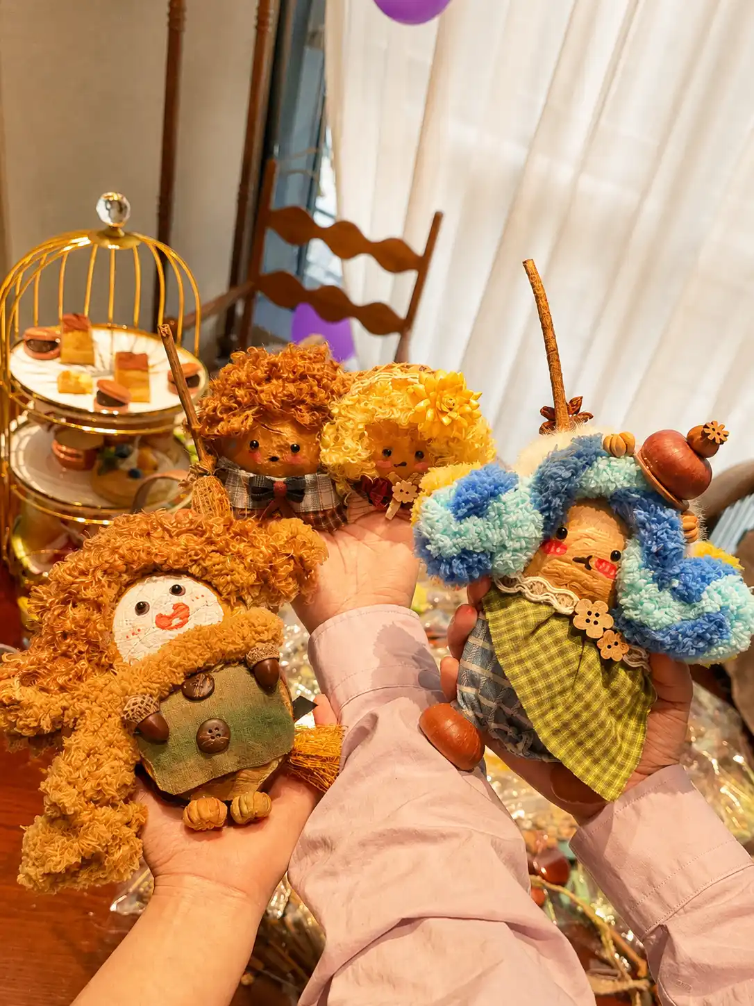 Several hands holding four different handmade Poddoll characters at an indoor celebration