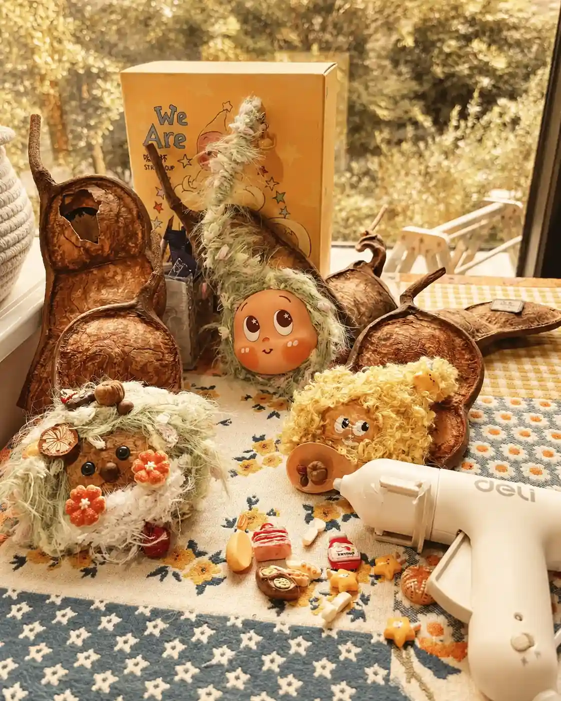 Handmade Poddoll characters and natural seed pod shells on a studio worktable