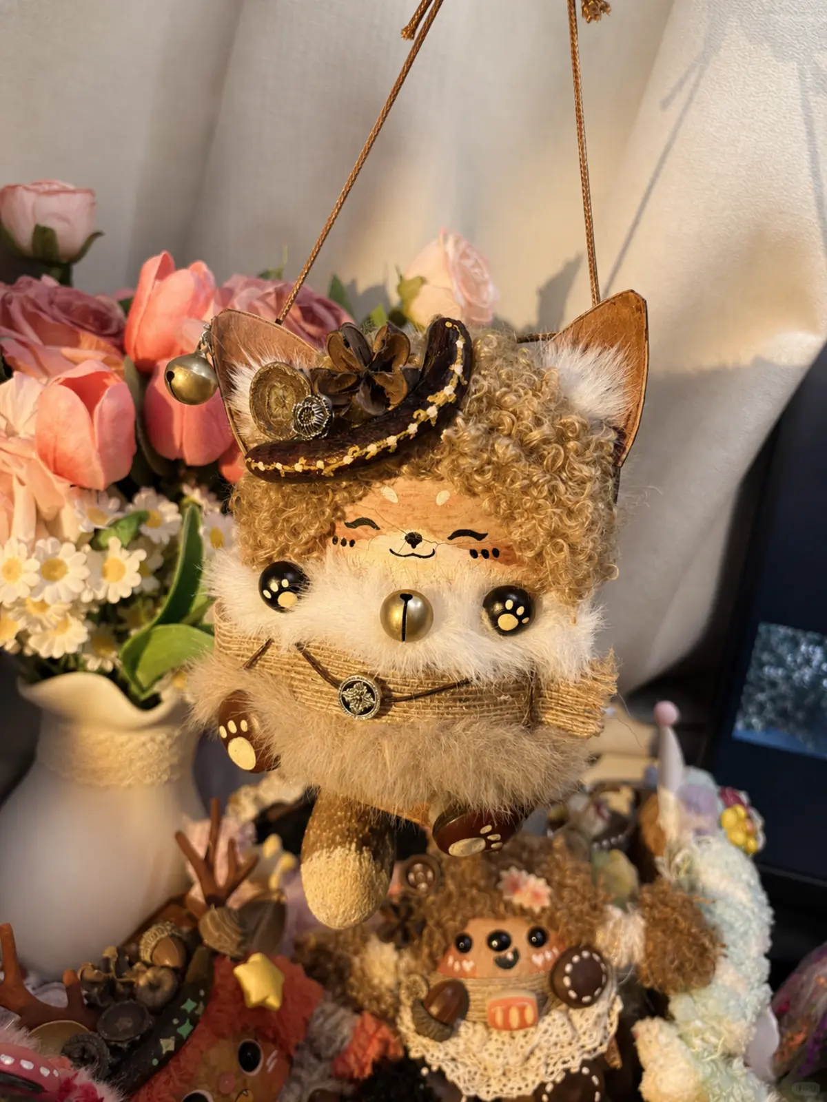 Hanging handmade cat Poddoll displayed among flowers and small character dolls