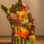 Close-up of a light-up miniature forest Poddoll with a fairy, fox, mushrooms, butterflies, moss, and a small wooden fence
