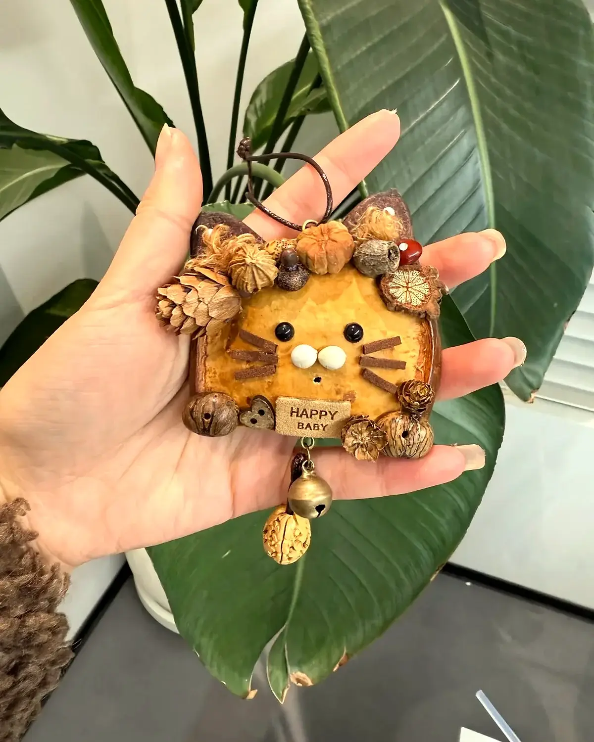 Natural handmade Poddoll detail with seed pod shell, pinecones, leaves, and small bell