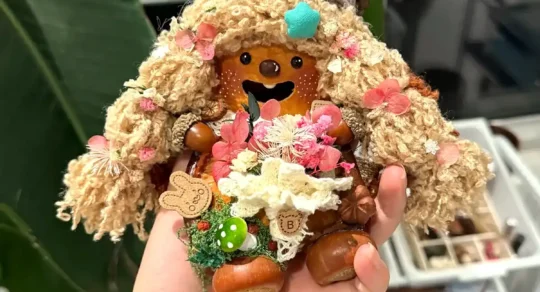 Small handmade Poddoll gift held in one hand with natural details