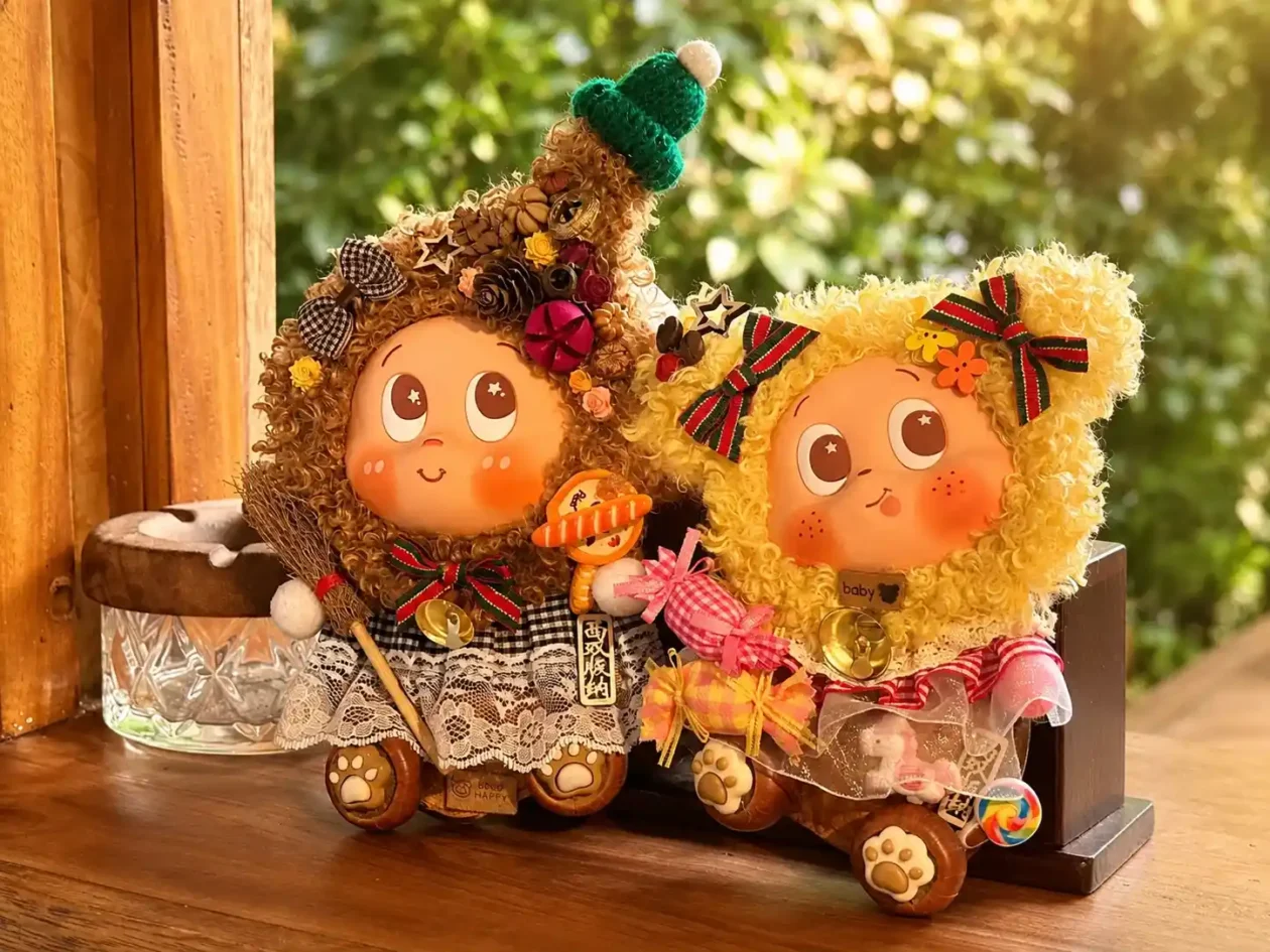 Two finished handmade Poddolls with brown and yellow curly hair, bows, lace clothing, bells, and small character accessories