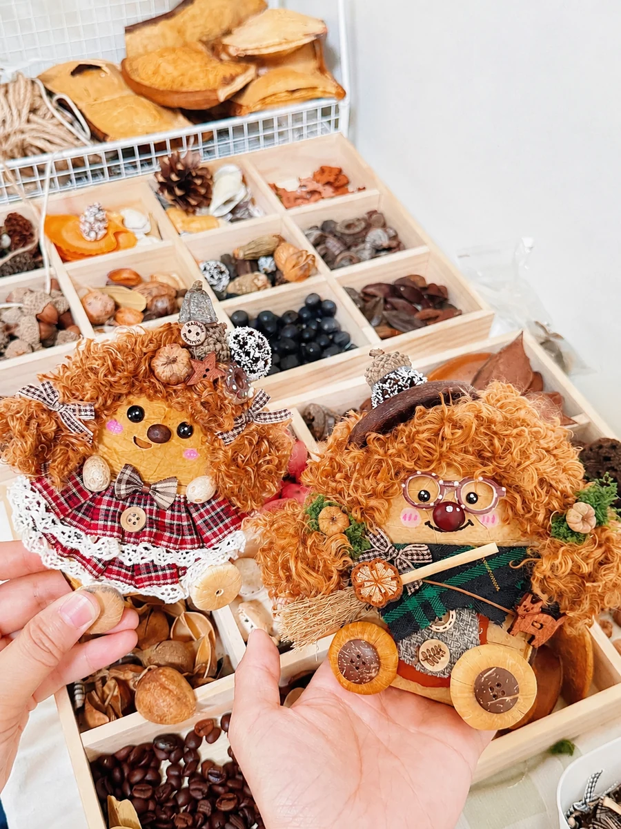 Two handmade Poddolls displayed beside natural materials at a studio worktable