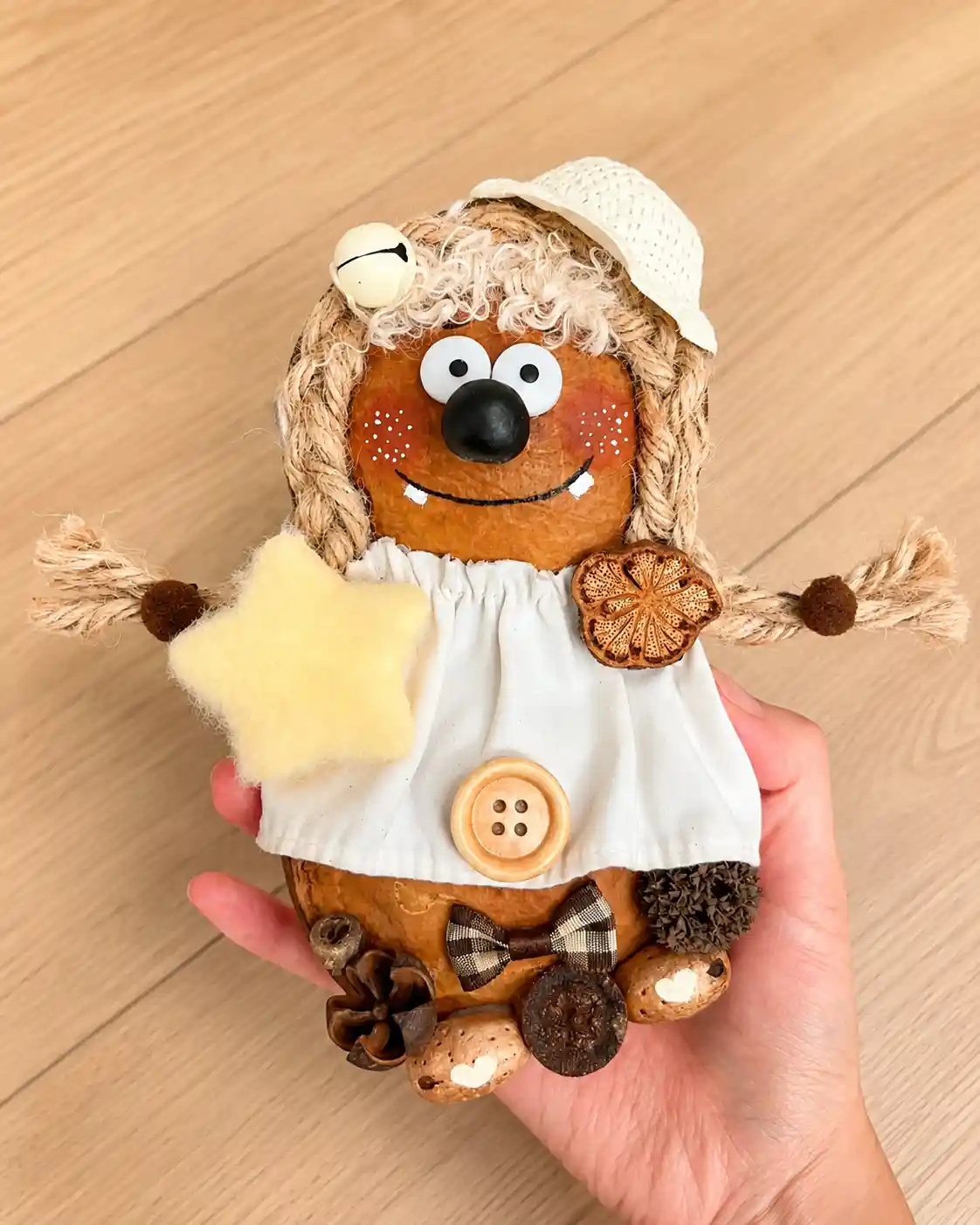 Handmade person-like Poddoll wearing a white dress and hat while holding a soft yellow star