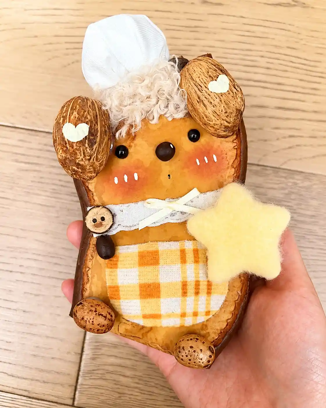 Handmade dog-like Poddoll with floppy seed pod ears, a yellow star, white hat, and yellow plaid outfit